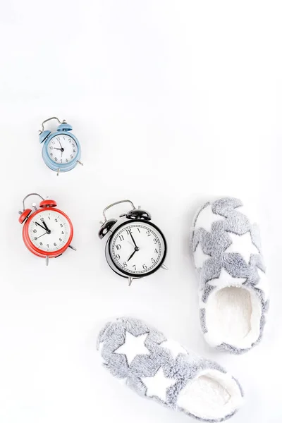 Soft fluffy slippers and alarm clocks — Stock Photo, Image