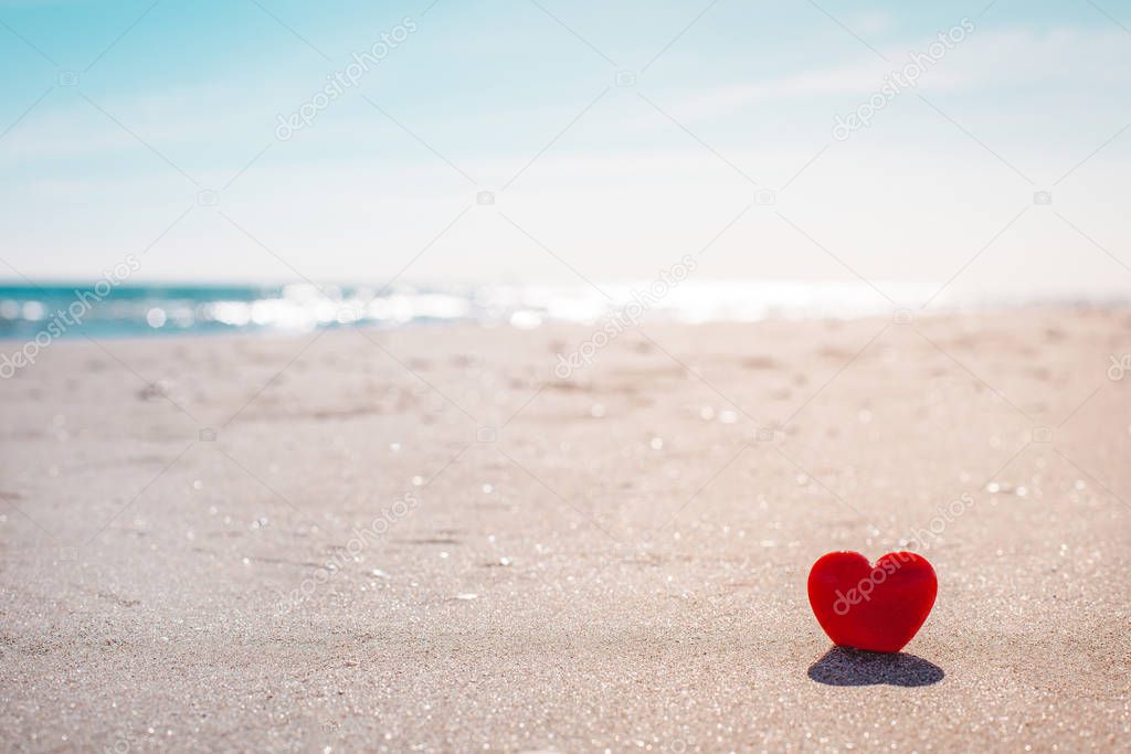 Romantic symbol of red heart on the sand beach
