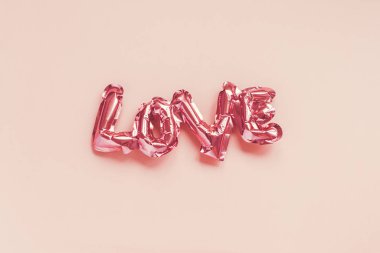 Aşk konsepti. Üzerinde harfler olan şişme pembe bir balon.