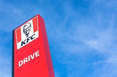 KFC Kentucky Fried Chicken Drive fast food restoranının logosu Fransa 'nın Lyon alışveriş bölgesinde yer alıyor. Kopya alanı olan parlak mavi gökyüzü arkaplanı. Lyon, Fransa - 23 Şubat 2020