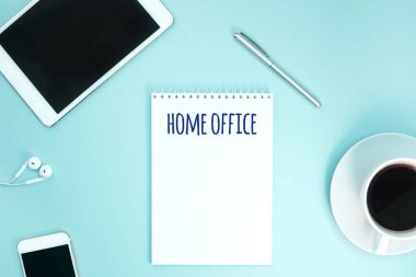 Kağıt defter, akıllı telefon, kulaklık, kalem ve kahve ile çalışma masasının yaratıcı düz fotoğrafı. Coronavirus pandemik karantina izolasyonu sırasında evden çalışma. Uzaktan kumandalı ev konsepti