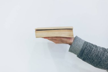 Genç adam elinde beyaz arka plan üzerine eski bir kağıt defteri tutuyor.