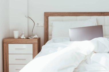 Ev karantinasında çalışmak kendini tecrit etme kavramı. Dizüstü bilgisayar yapılmamış yatakta. Rahat ve uzaktan kumandalı ev ofisi. Günışığı ve minimalist tasarımı olan modern daireler. Salgında güvende ol..