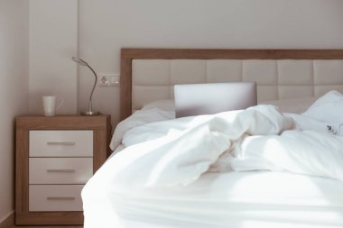 Ev karantinasında çalışmak kendini tecrit etme kavramı. Dizüstü bilgisayar yapılmamış yatakta. Rahat ve uzaktan kumandalı ev ofisi. Günışığı ve minimalist tasarımı olan modern daireler. Salgında güvende ol..