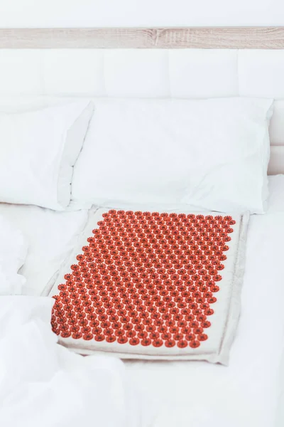 Acupuncture mat in bed. Wellness, reflexology and self care treatment at home concept. Alternative therapy massager with acupressure points. Reduce muscle tension, back pain, improve blood circulation