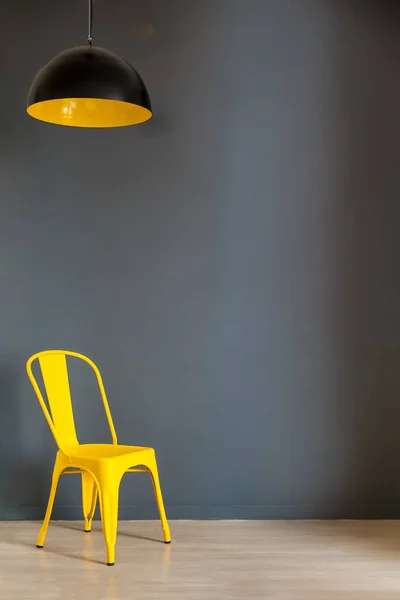 Living room wall mock up with dark grey wall and bold yellow chair and lamp