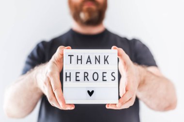 Nurse day concept. Man hands holding lightbox with Thank heroes text thanking doctors, nurses and medical staff working in hospitals during coronavirus COVID-19 pandemics. clipart