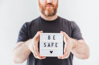 Sağlık ve Güvenlik konsepti. Elinde yazı olan adam Coronavirus COVID-19 salgınında dikkatli ol.