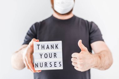 Hemşire günü konsepti. Erkek eller ışık kutusunu mesajla tutarken hemşirelerinize Coronavirus COVID-19 salgını sırasında hastanede çalışan doktorlara, hemşirelere ve sağlık personeline teşekkür edin.