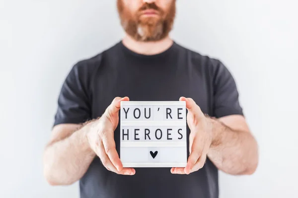 Nurse day concept. Man hands holding lightbox with You are heroes text thanking doctors, nurses and medical staff working in hospitals during coronavirus COVID-19 pandemics.