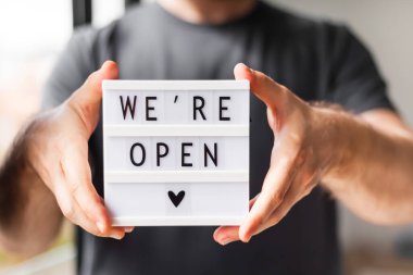 Karantina sona erdi. Elinde selamlama mesajı olan bir adam var. Onun ellerinde açığız. Otel, kafe, yerel dükkan, hizmet sahibi Coronavirus salgınından sonra misafirleri karşılıyor ve insanlar kapanıyor..