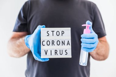 El hijyen önleyici alkol jeli şişeleri ve ışık kutusu. Coronavirus 'u durdurun. Koronavirüs COVID 19 salgını sırasında lateks eldiven ve koruyucu maske takan adamın ellerinde. Sağlık Hizmetleri