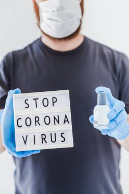 El hijyen önleyici alkol jeli şişeleri ve ışık kutusu. Coronavirus 'u durdurun. Koronavirüs COVID 19 salgını sırasında lateks eldiven ve koruyucu maske takan adamın ellerinde. Sağlık Hizmetleri