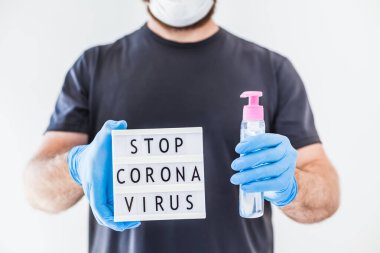 El hijyen önleyici alkol jeli şişeleri ve ışık kutusu. Coronavirus 'u durdurun. Koronavirüs COVID 19 salgını sırasında lateks eldiven ve koruyucu maske takan adamın ellerinde. Sağlık Hizmetleri