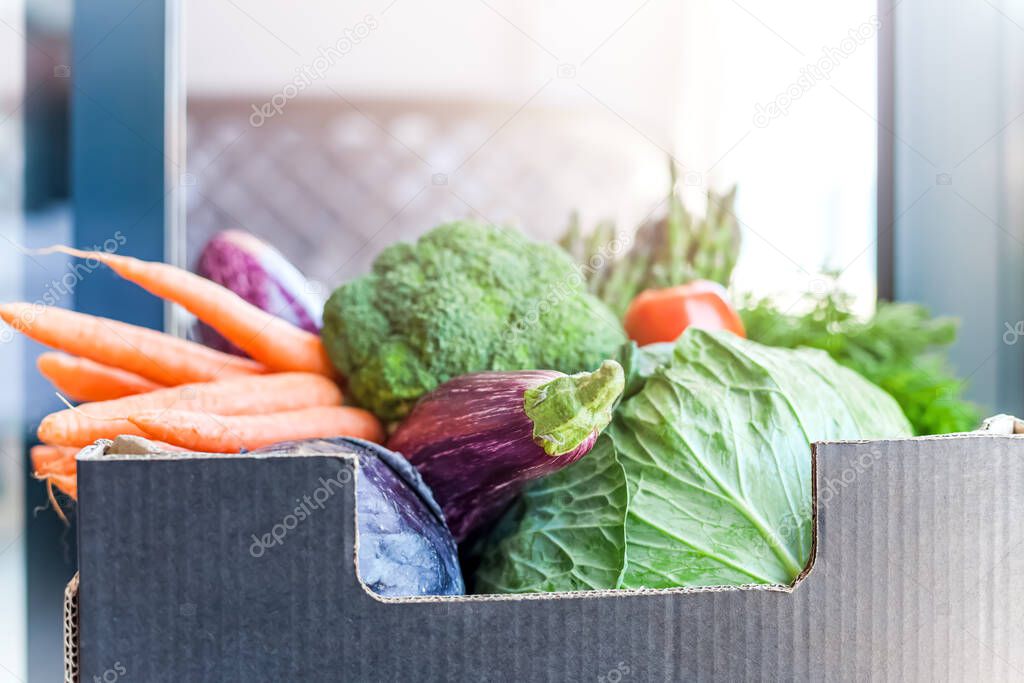 Fresh organic greens and vegetables safe contactless delivery during coronavirus Covid-19 pandemic outbreak. Box with grocery delivering left in the house doorway
