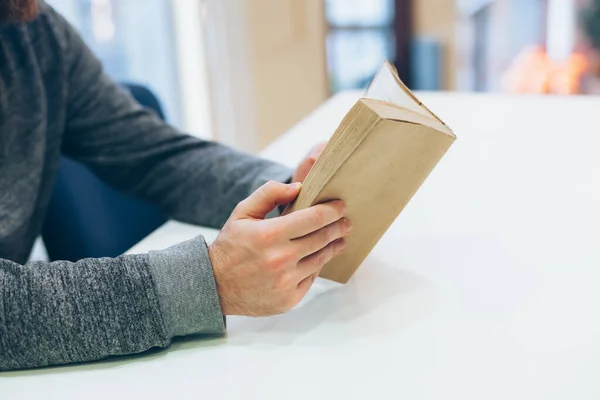 Young man holding close old paper book on white background with copy space. Spending time home during quarantine isolation. Education concept