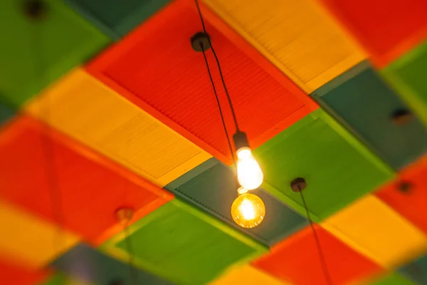 Round stylish lampshades hang from colorful yellow, green and re — Stock Photo, Image