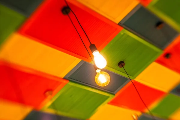 Round stylish lampshades hang from colorful yellow, green and re — Stock Photo, Image