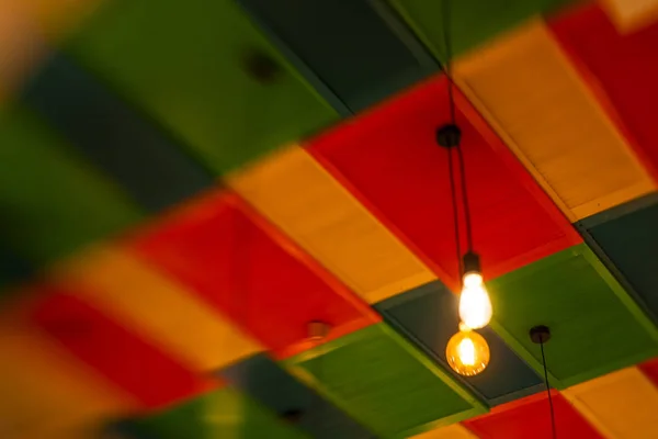 Round stylish lampshades hang from colorful yellow, green and re — Stock Photo, Image