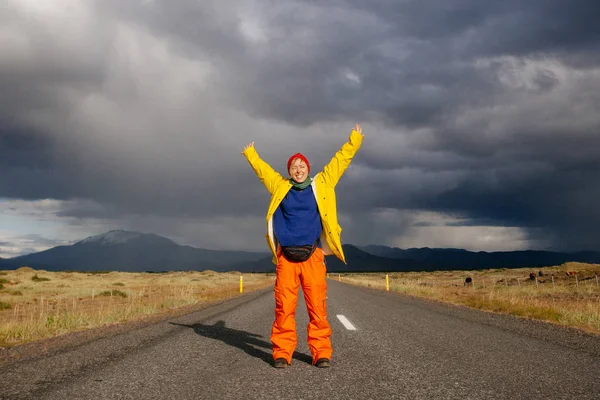Счастливая туристическая женщина в яркой одежде и желтом пальто, наслаждаясь — стоковое фото