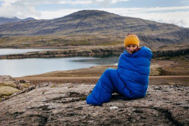 Kuzey taşlarla üzerinde sıcak mavi uyku tulumu içinde genç kadın