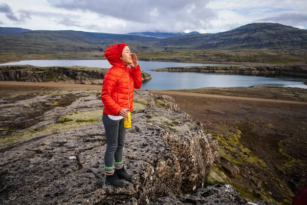 Icelan에는 이끼와 돌에 빨간 코트에 젊은 여자 — 스톡 사진