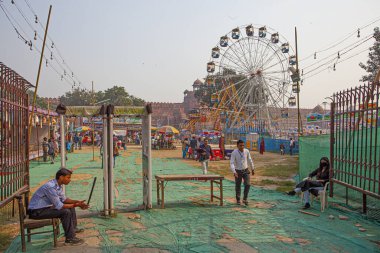 DELHI, INDIA - 21 Kasım 2019: İnsanlar kırmızı kalenin önündeki Delhi, Hindistan 'daki lunaparktaki büyük tekerleğin tadını çıkarıyorlar. Fiyatlar çok düşük, daha fakir insanların binmesine olanak sağlıyor..