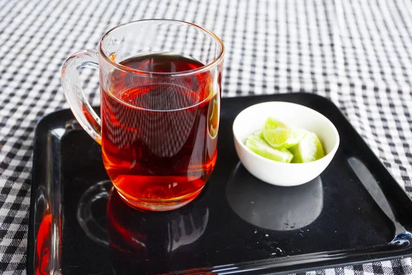 Black tea and slices lemon on the black plate