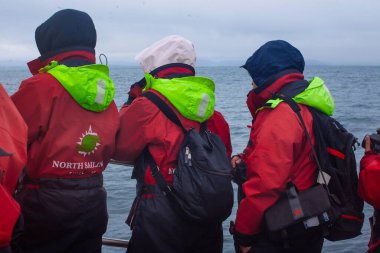 Husavik, İzlanda, 17 Ağustos 2017: Küçük bir sürat teknesinde balina turu izleyen turistler. Hepsi eşleşen sıcak tulumlar giyiyor..