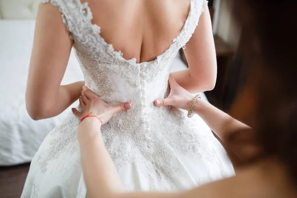 Dama de honra está ajudando a noiva a se vestir — Fotografia de Stock