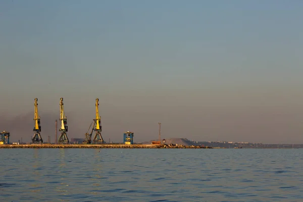 Многие большие краны силуэт в порту при золотом свете заката. Мариуполь, Украина — стоковое фото