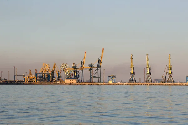 Muchas grandes grúas silueta en el puerto a la luz dorada de la puesta del sol. Mariupol, Ucrania — Foto de Stock