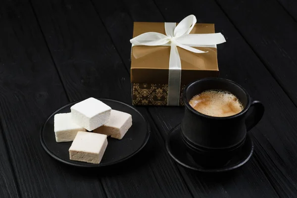 Marshmallow op een zwarte lijst met gouden geschenk doos en koffie kopje — Stockfoto