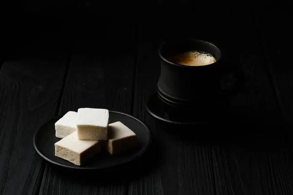 Marshmallow in een zwarte plaat op zwarte houten tafel — Stockfoto