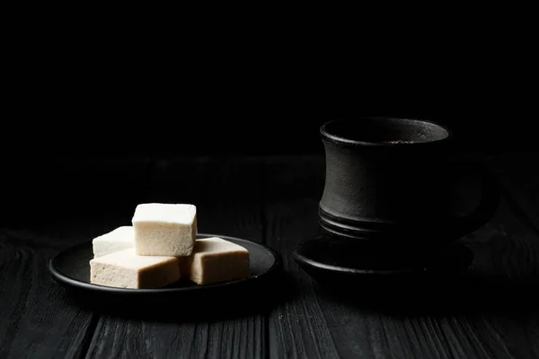 Marshmallow in een zwarte plaat op zwarte houten tafel — Stockfoto