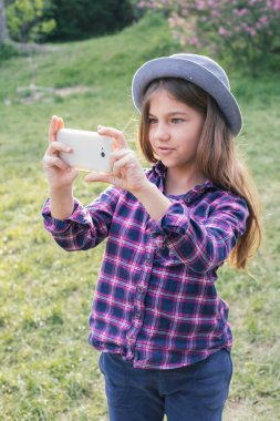Bahar parkta onun smartphone ile sevimli pre-teen yayılmalı esmer çocuk kız