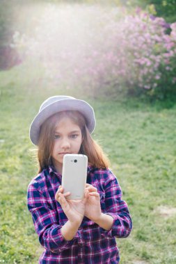 Bahar parkta onun smartphone ile sevimli pre-teen yayılmalı esmer çocuk kız