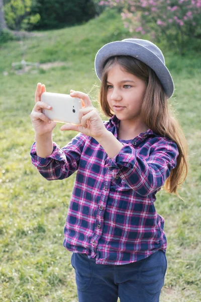 Bedårande pre-Teen tweenie brunett kid flicka med sin smartphone i parken våren — Stockfoto