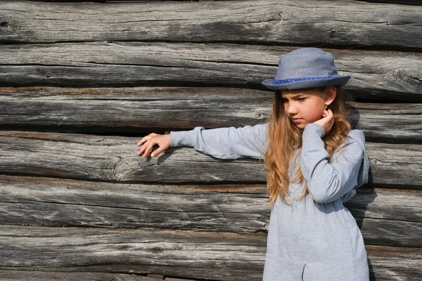 Радостная девочка-подросток в повседневной одежде и синей шляпе, позирующей у деревянной стены. Активный образ жизни. Мода молодежи — стоковое фото