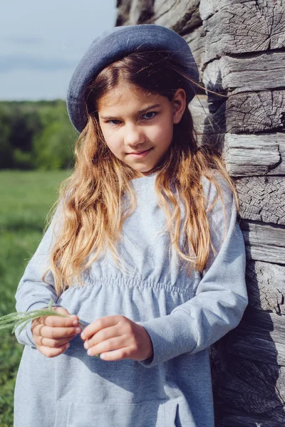 Joyful teen girl in casual clothes and blue hat posing by a wooden wall. Active lifestyle. Youth fashion — Stock Photo, Image