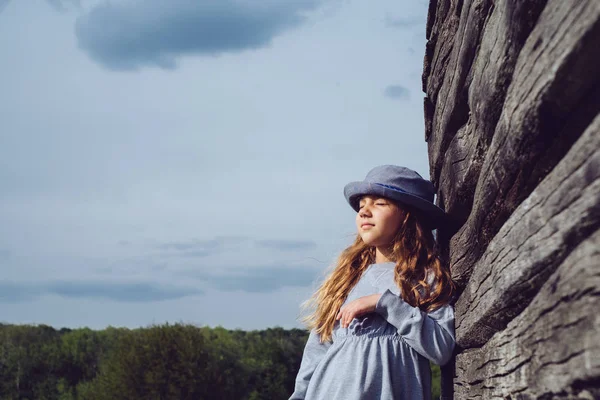Teen dívka v neformálním oblečení a Modrý klobouk sny opírající se o dřevěné zdi. Aktivní životní styl. Móda mladých — Stock fotografie