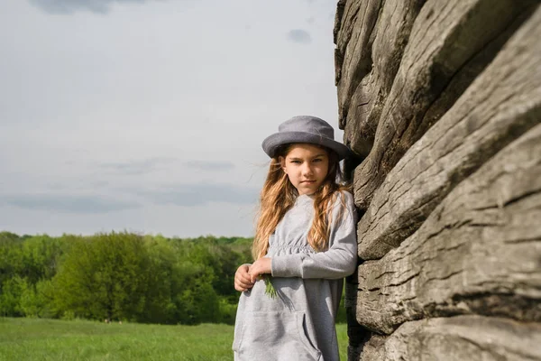 Örömteli tini lány alkalmi ruhák és kék kalapban pózol egy Wood — Stock Fotó