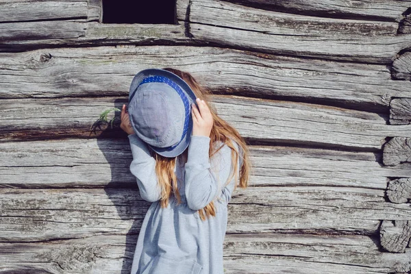 Joyful teen girl in casual clothes and blue hat posing by a wooden wall. Active lifestyle. Youth fashion — Stock Photo, Image