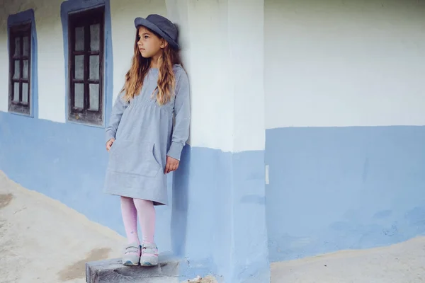 Tini lány alkalmi ruhák és kék kalapot közelében, a Faluház — Stock Fotó