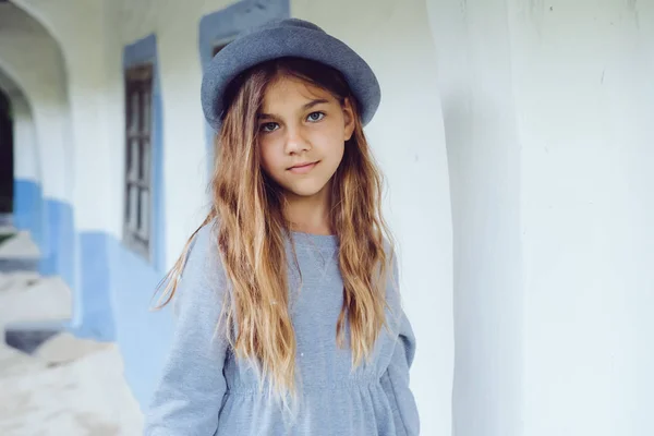 Девочка-подросток в повседневной одежде и синей шляпе рядом с деревенским домом — стоковое фото