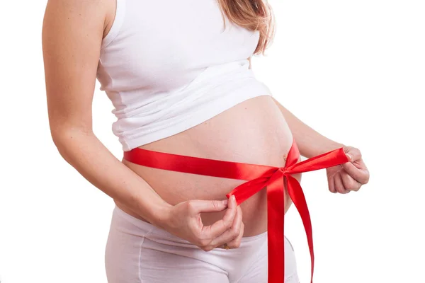 Stomachs of pregnant women tied a red scarlet ribbon isolated on white — Stock Photo, Image