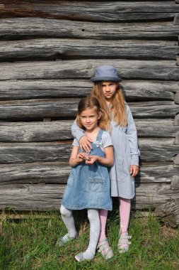 Ahşap duvar tarafından poz mavi rahat kıyafetler'de iki neşeli kız kız. Aktif yaşam tarzı. Gençlik moda