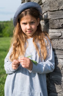 Neşeli genç kız rahat kıyafetler ve ahşap duvar tarafından poz mavi şapka. Aktif yaşam tarzı. Gençlik moda