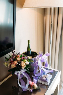 Düğün buketi, bir yaka çiçeği, bir şişe şampanya vardır masada