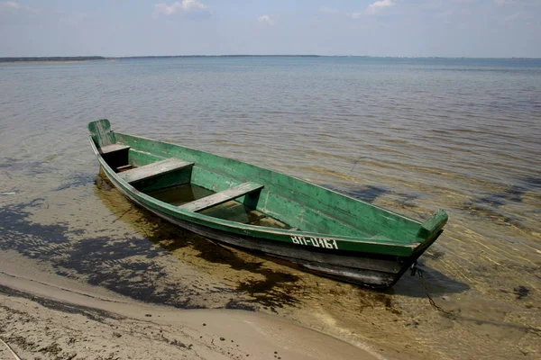 Boat moored with chains at river shore. water transportation. green lake flora in summer. — Stock Photo, Image